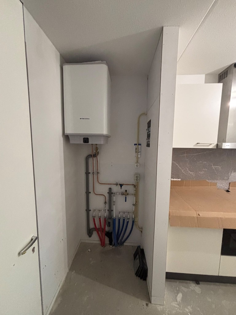 Cv-ketel met koperen en kunststof leidingen in een technische ruimte.
